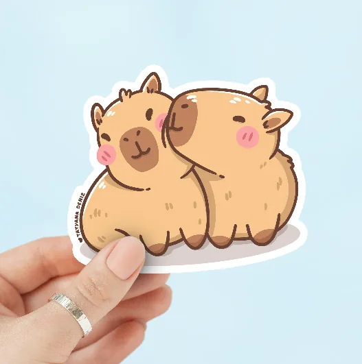 Hand holding a die-cut capybara sticker